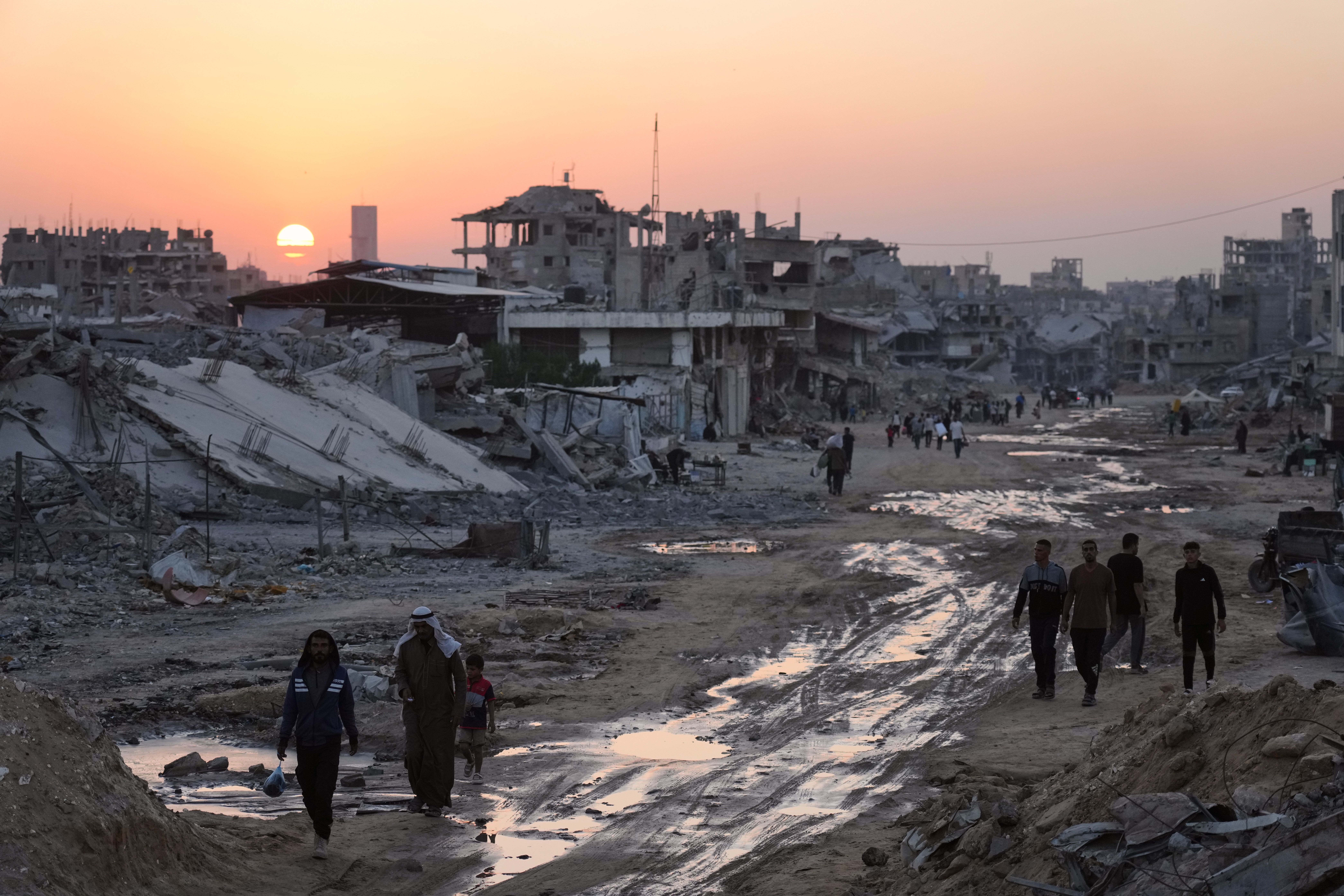 Palestinians walk among destroyed buildings in Khan Younis, southern Gaza Strip, on Sunday.